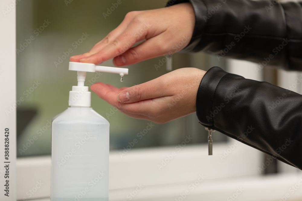 Female hand pressing bottle and pouring alcoholbased sanitize on hands