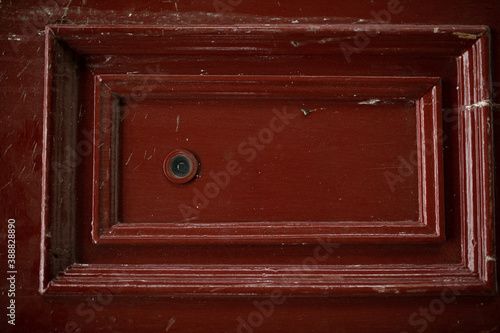 front view closeup of vintage metallic view finder on blown scratched wooden door texture