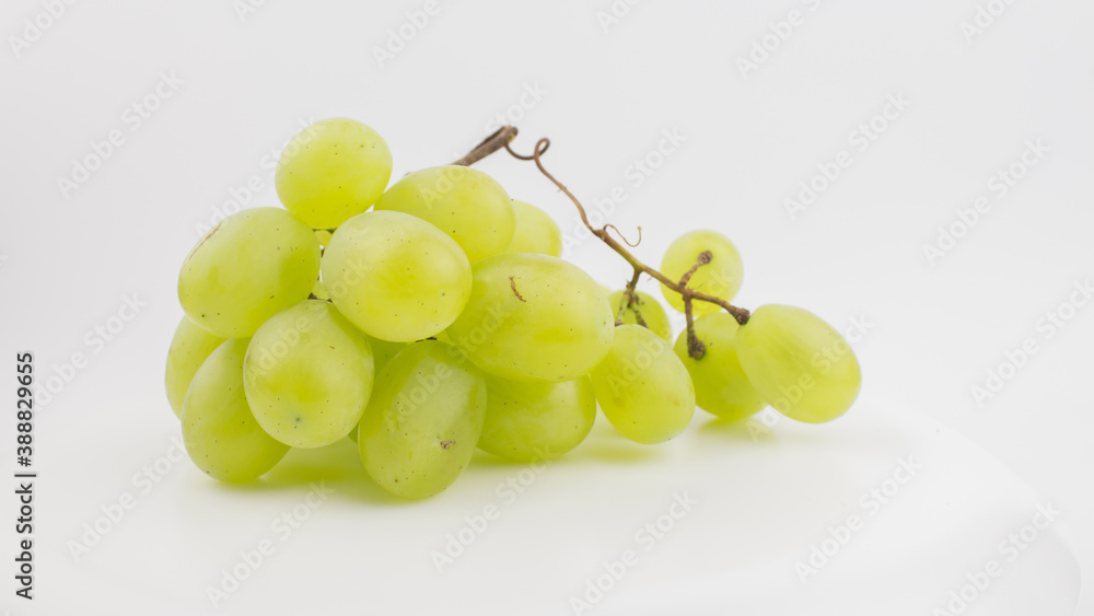 Fresh bunch of juicy grapes rotate on a white background. Ripe juicy grapes rotate on a plate. Close-up of a bunch of white grapes. Fresh bunch of juicy grapes rotate on a white background. Ripe juicy grapes rotate on a plate. Close-up of a bunch of white grapes.