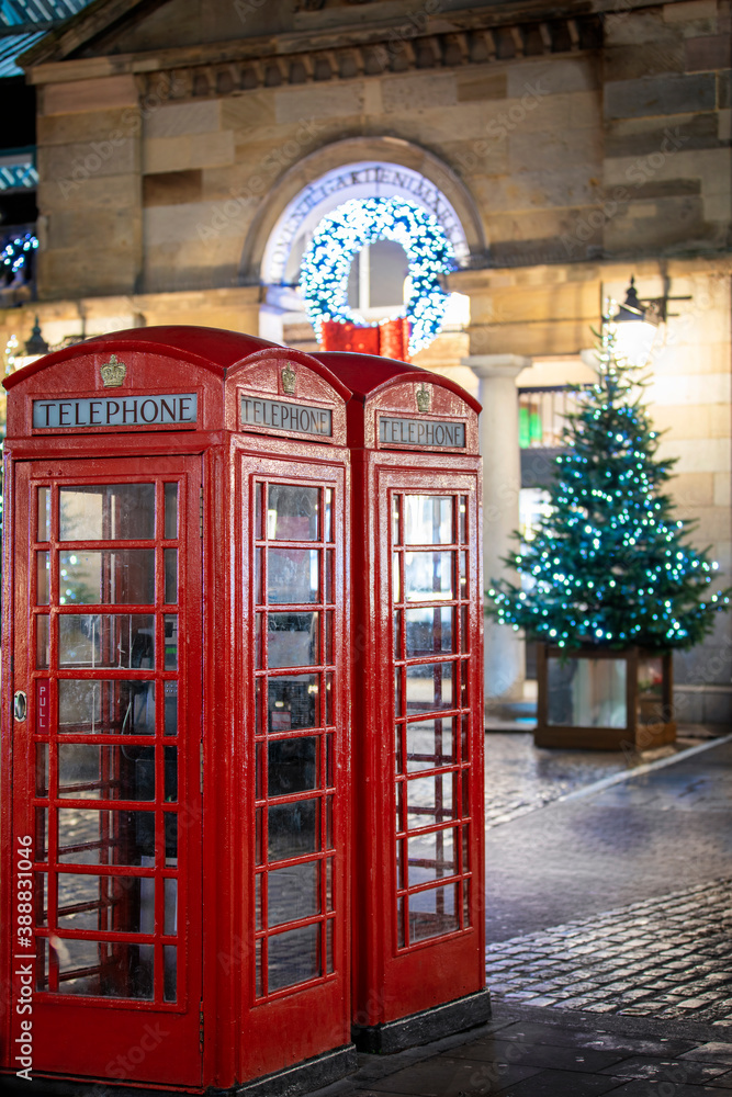 Red telephone booths in front of Christmas decorations lights in the Covent Garden district, London, United Kingdom