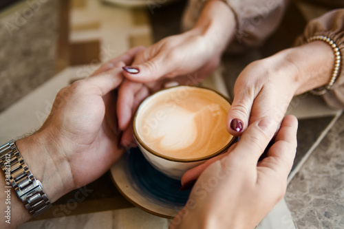 Man and woman holding hands on a coffee cup. Love concept.
