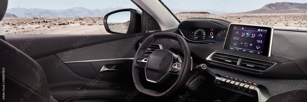 Cockpit of a modern SUV with a view of the desert and mountains. In the mirror you can see the road on which it stands.