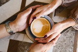 Man and woman holding hands on a coffee cup. Love concept.