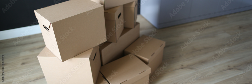 Close-up of empty carton boxes on floor. Cardboard with personal stuff. Delivery service. Stack of closed containers. Moving day and renovation in apartment concept Close-up of empty carton boxes on floor. Cardboard with personal stuff. Delivery service. Stack of closed containers. Moving day and renovation in apartment concept