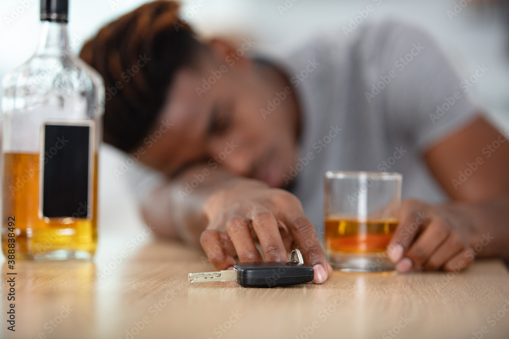 man hand holding car keys over whiskey glass man hand holding car keys over whiskey glass