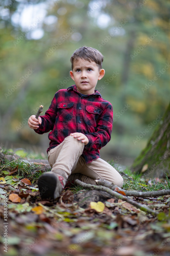 Little beautiful boy sitting on the ground in a forest hurt Little beautiful boy sitting on the ground in a forest hurt