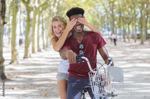 mixed couple playing on a bicycle outdoors