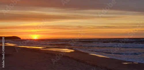 piekny zachód zlońca. Pomarańczowe niebo i cieple światło ślońca na piaszczystej plazy