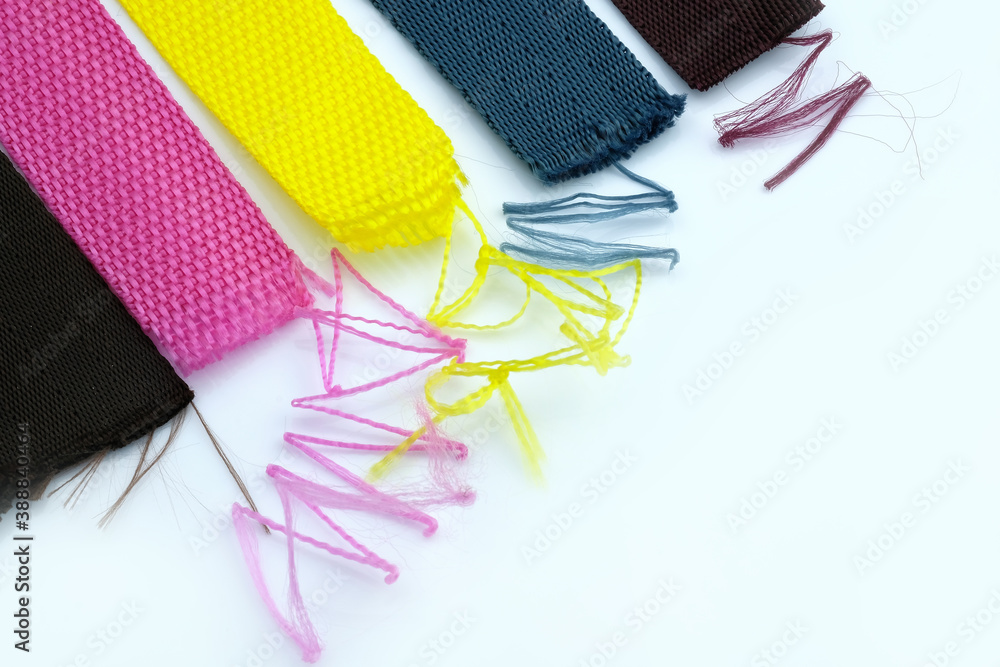 Multicolored textile belts with threads sticking out on a white