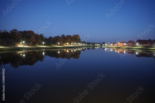 nocny widok na oświetlone lampami jezioro 