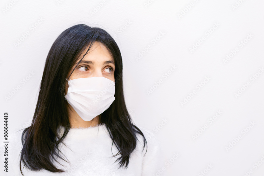 Close up of Young caucasian woman wearing white mask and looking to the right side of white blank space area. Close up of Young caucasian woman wearing white mask and looking to the right side of white blank space area.