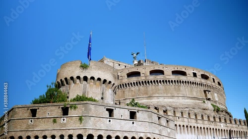 The panoramic view on the exciting medieval fortification Castel Sant Angelo with its ancient watchtower, the collosal statue of Angel Michael on the top and the flattering flag of the united Europe photo