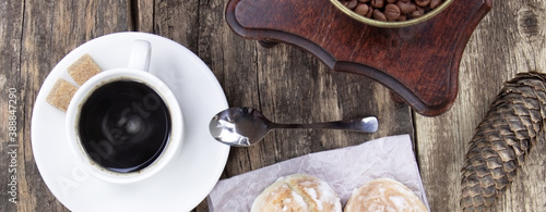 A white cup of coffee and cake on a wooden background. Banner. A coffee grinder on a wooden table, Cone