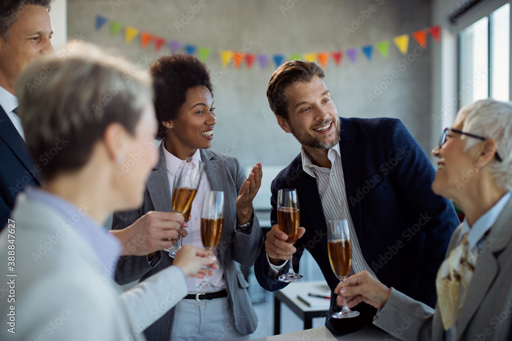 Happy business team talking while drinking Champagne at office party. Happy business team talking while drinking Champagne at office party.