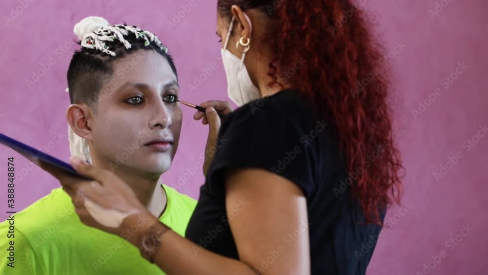 Makeup artist with a mask putting makeup on a man for halloween Makeup artist with a mask putting makeup on a man for halloween