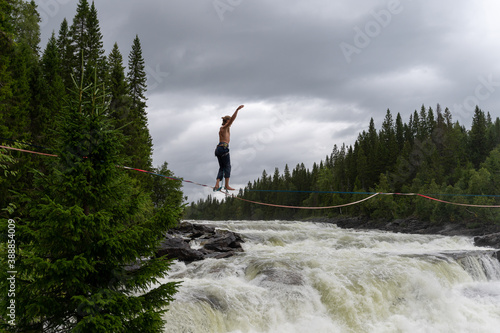 Man walking a tightrope across the tannforsen waterfall in Sweden trying to keep his balance photo