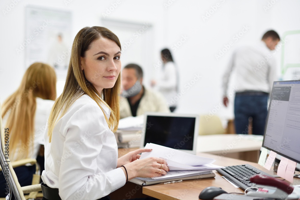 Portrait of middle aged woman office manager at workplace in office with people Portrait of middle aged woman office manager at workplace in office with people