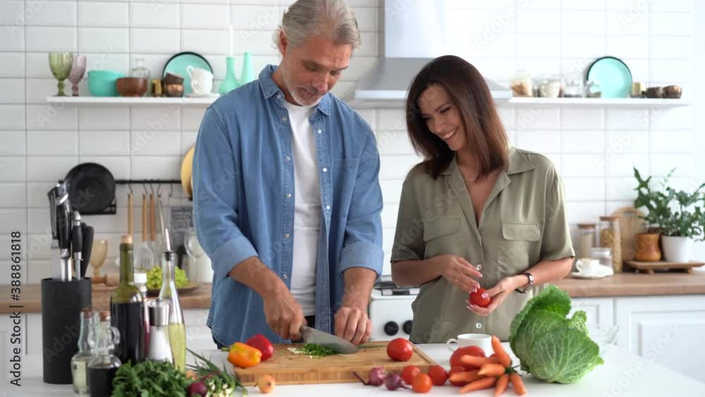 Portrait of happy couple cooking together at home. Married couple flirting at home kitchen. Man and woman cooking breakfast at modern apartment. Portrait of happy couple cooking together at home. Married couple flirting at home kitchen. Man and woman cooking breakfast at modern apartment.