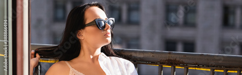 brunette woman in sunglasses sunbathing on balcony, horizontal banner