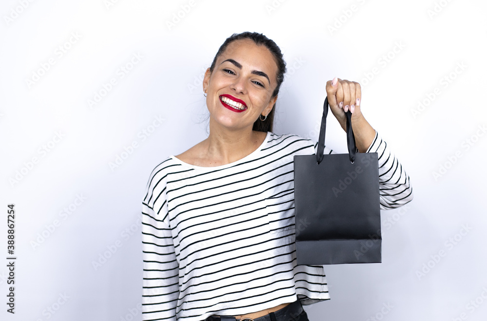 Young beautiful woman holding a black shopping bag smiling to the camera. Black Friday Young beautiful woman holding a black shopping bag smiling to the camera. Black Friday