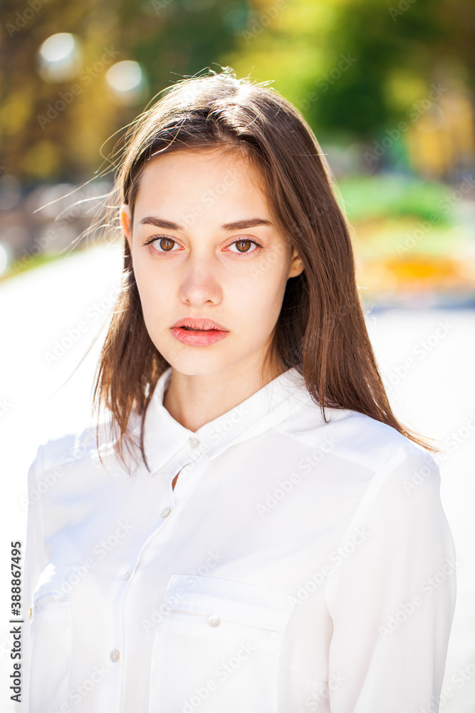 Close up portrait of a young brunette girl in white shirt