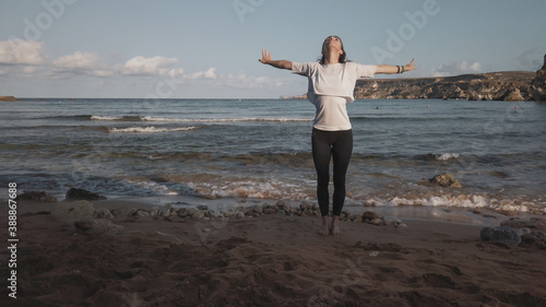 Young caucasian brunette woman doing youga on the sandy beach in the morning. High quality photo