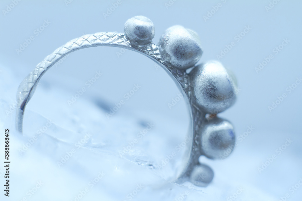 Close-up silver ring frozen into ice on white background, selective focus Close-up silver ring frozen into ice on white background, selective focus