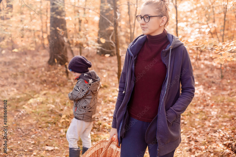 Obraz premium Woman with son in the autumn forest on a walk. Girl in the woods.