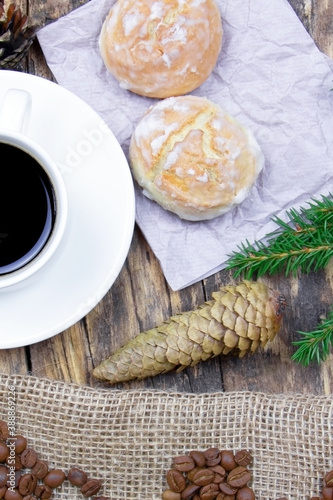 A white cup of coffee and cakes on a wooden background. Coffee beens on a linen fabric. Breakfast coffee. Fir branch