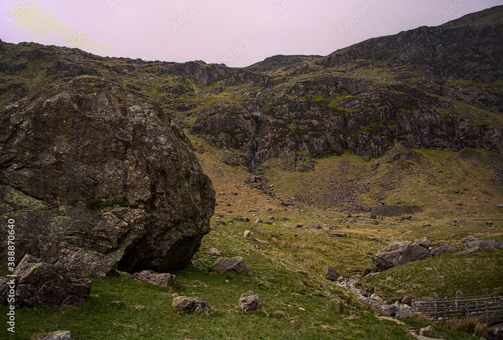 A giant rock wall with a narrow waterfall in the middle