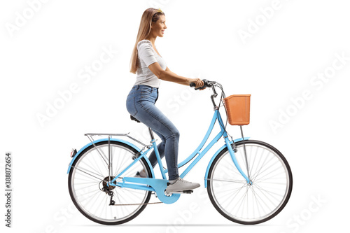 Full length profile shot of a young woman with long hair riding a bicycle