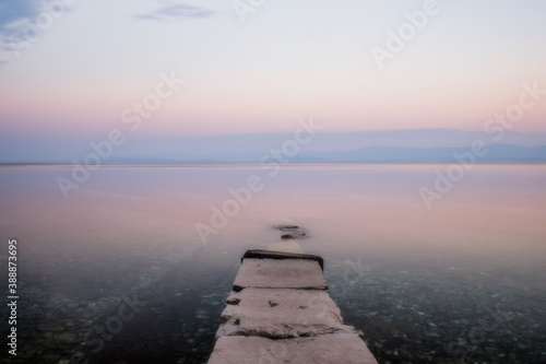 Stone pier with a boat in long exposure  low saturation. Croatia  Brac island  Supetar at sunrise. August 2020