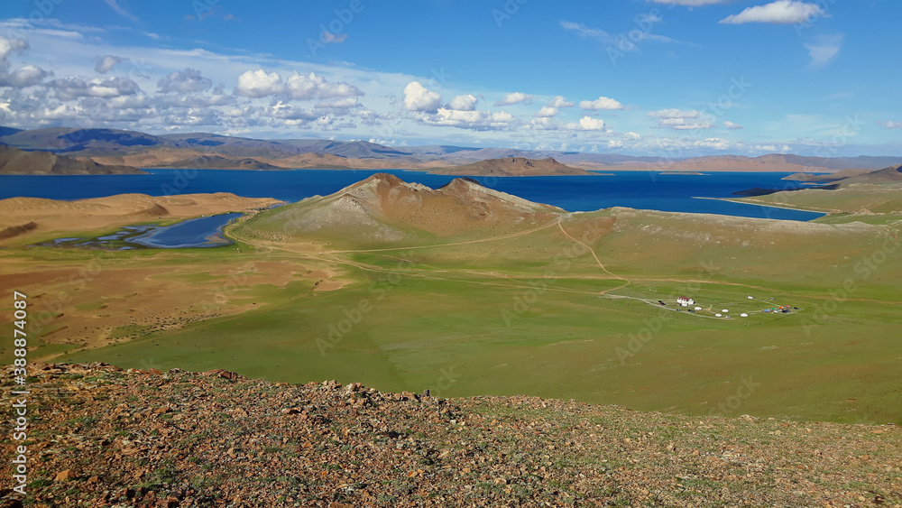 Stunning Mongolian landscape compromised of plains, sand dunes and a lovely blue lake under a blue sky