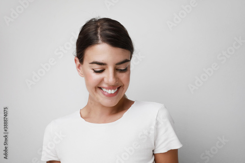 Photos Happy young woman smiling wearing white T-shirt looking down