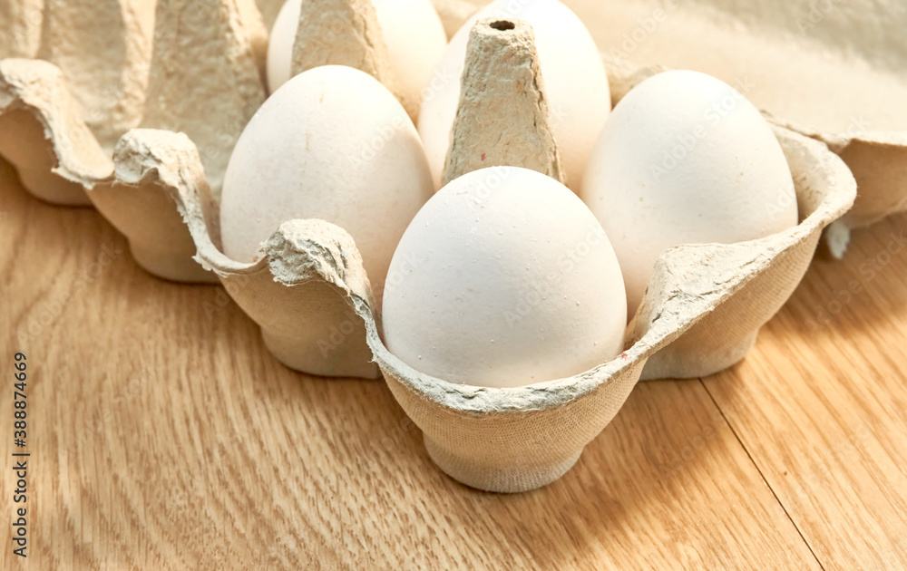 Raw chicken eggs in a cardboard box on the table.