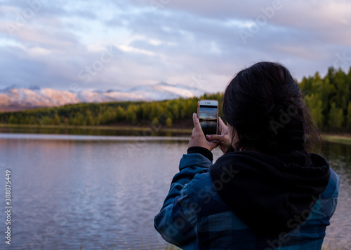 Wallpaper Mural young girl traveler photographs a beautiful landscape with snowy mountains Torontodigital.ca