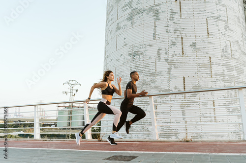 Canvas Print Multiethnic athletes running in industrial cityscape