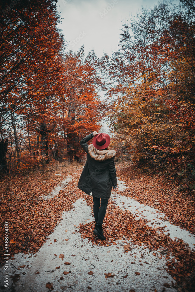 Beautiful woman holding autumn leaves as natural face mask, enjoying and exlploring the nature in autumn colors