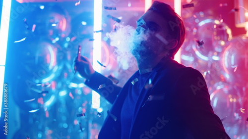 Relaxed guy smoking in nightclub. Man dancing with electronic cigarette at party