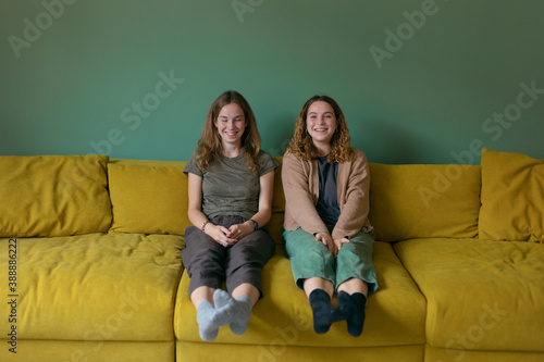 photo of two similar sisters on the couch. one laughs the other is shy. photo