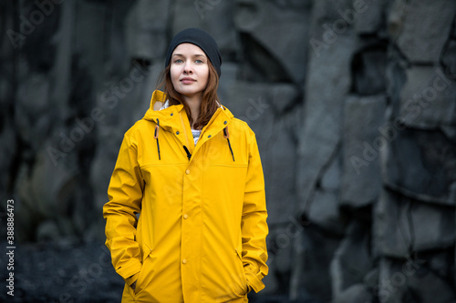 Woman in a yellow jacket on a background of basalt rocks, Iceland