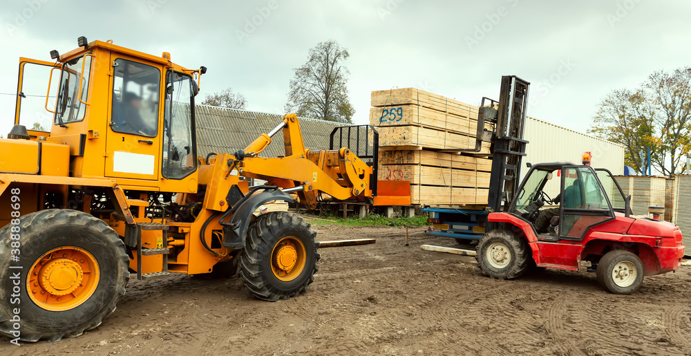 Two tractors load boards, lumber from the finished product warehouse into the container of the truck Two tractors load boards, lumber from the finished product warehouse into the container of the truck