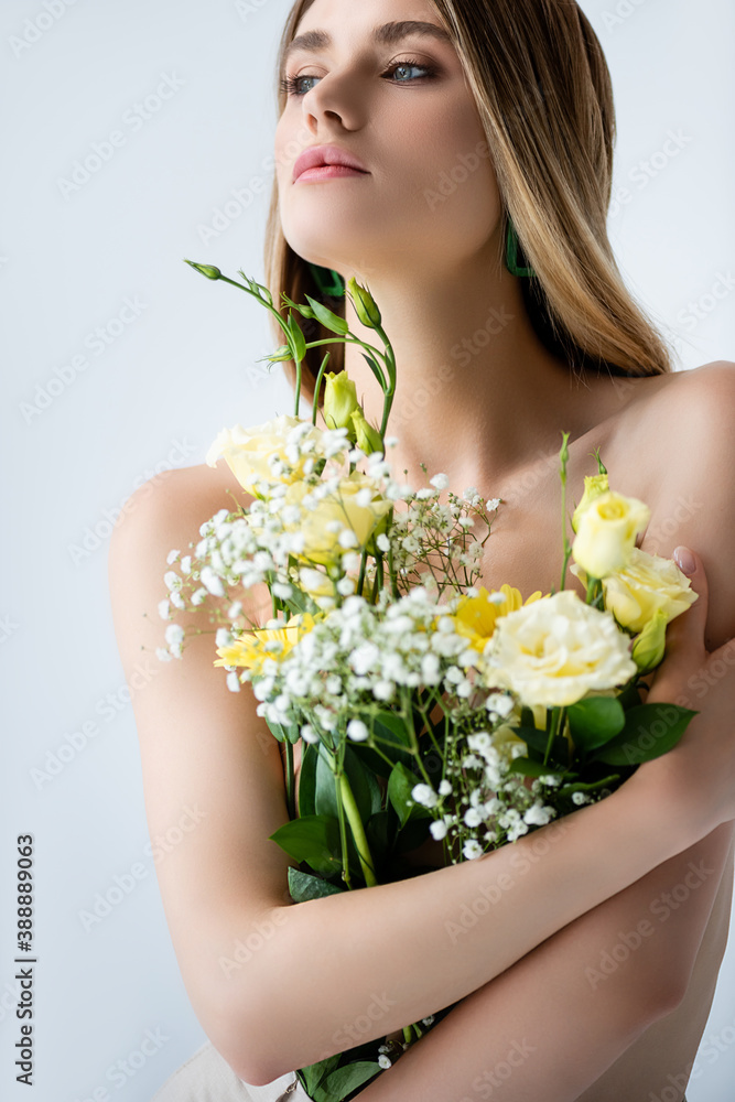 young model with naked shoulders embracing flowers on white