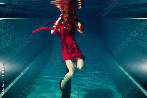 blurry woman wearing red dress underwater, strange and artistic, motion blur photo