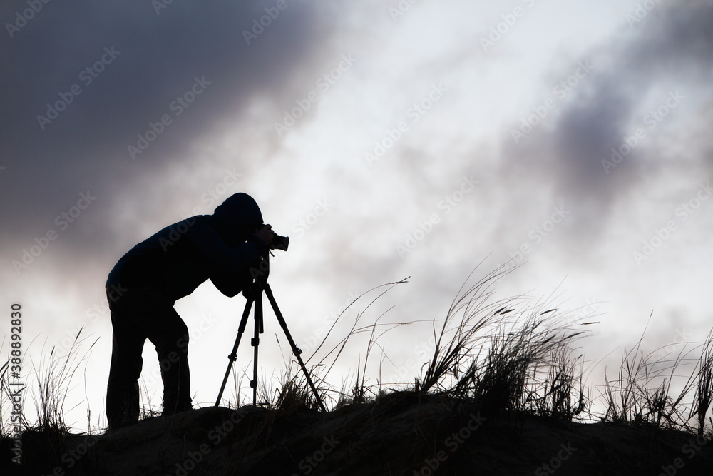 Silhouette of a photographer with a tripod against the sky with clouds Silhouette of a photographer with a tripod against the sky with clouds
