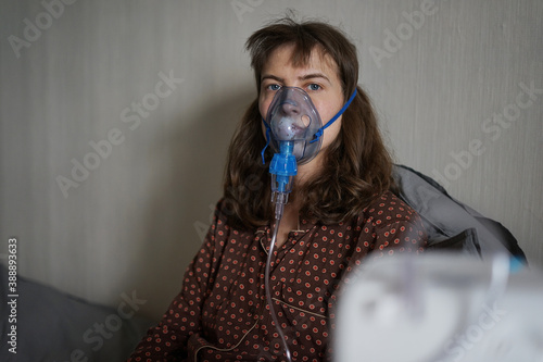 A young sick woman doing inhalation and looking at camera at home photo