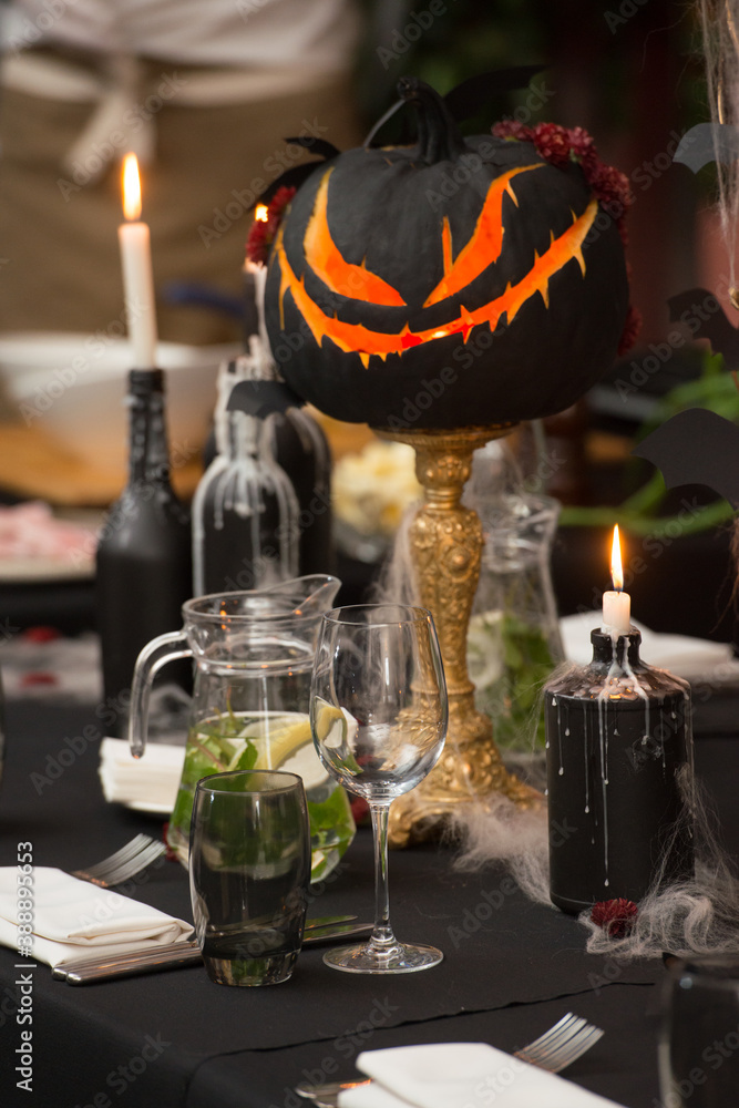 Table set for Halloween dinner. Served holiday table with candles and pumpkin