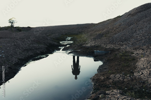 A haunted landscape of a ghostly reflection of a figure in water