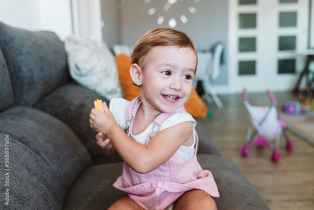 Baby girl holding biscuit while sitting on sofa at home Baby girl holding biscuit while sitting on sofa at home