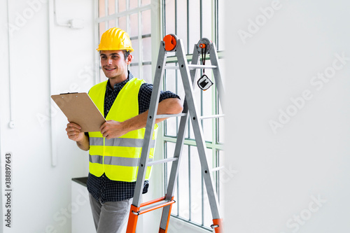Smiling architect leaning while standing by ladder at office under construction photo